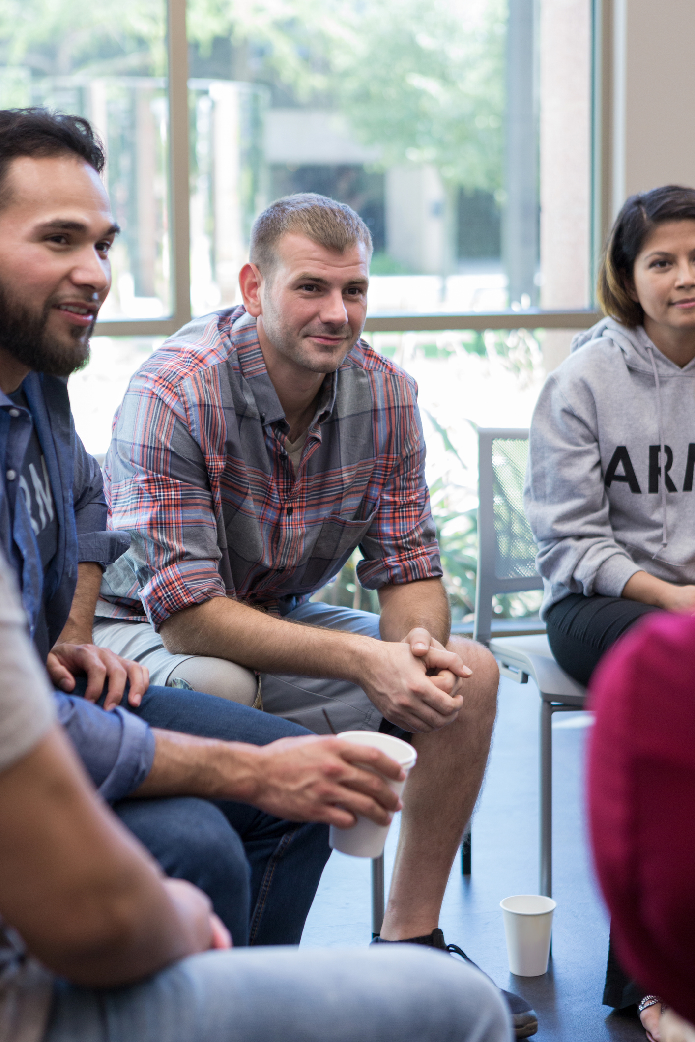 Male veteran listening attentively to a fellow veteran during a group therapy session, part of Pathway Healthcare’s supportive mental health services.