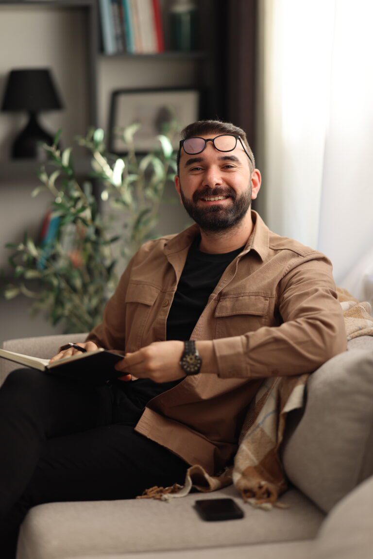 Man smiling during a therapy session with a psychologist, seated comfortably in a chair.