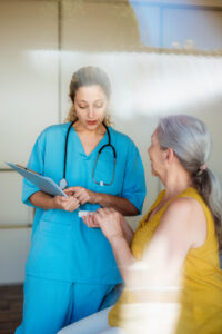 Nurse providing medical advice to senior woman in clinic, highlighting case management and supportive patient care.