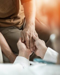 A picture of a mental health and addiction healthcare provider holding the hand of a patient in a supportive way.
