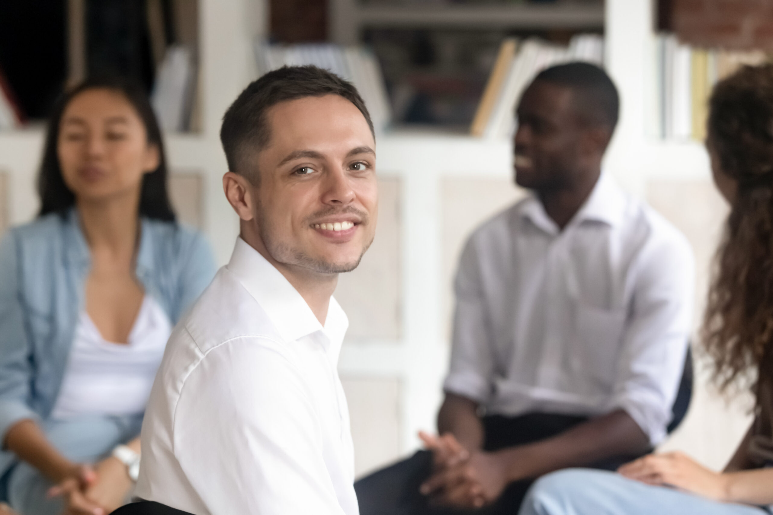 Content Caucasian man posing confidently during a group therapy session, showcasing a supportive environment.