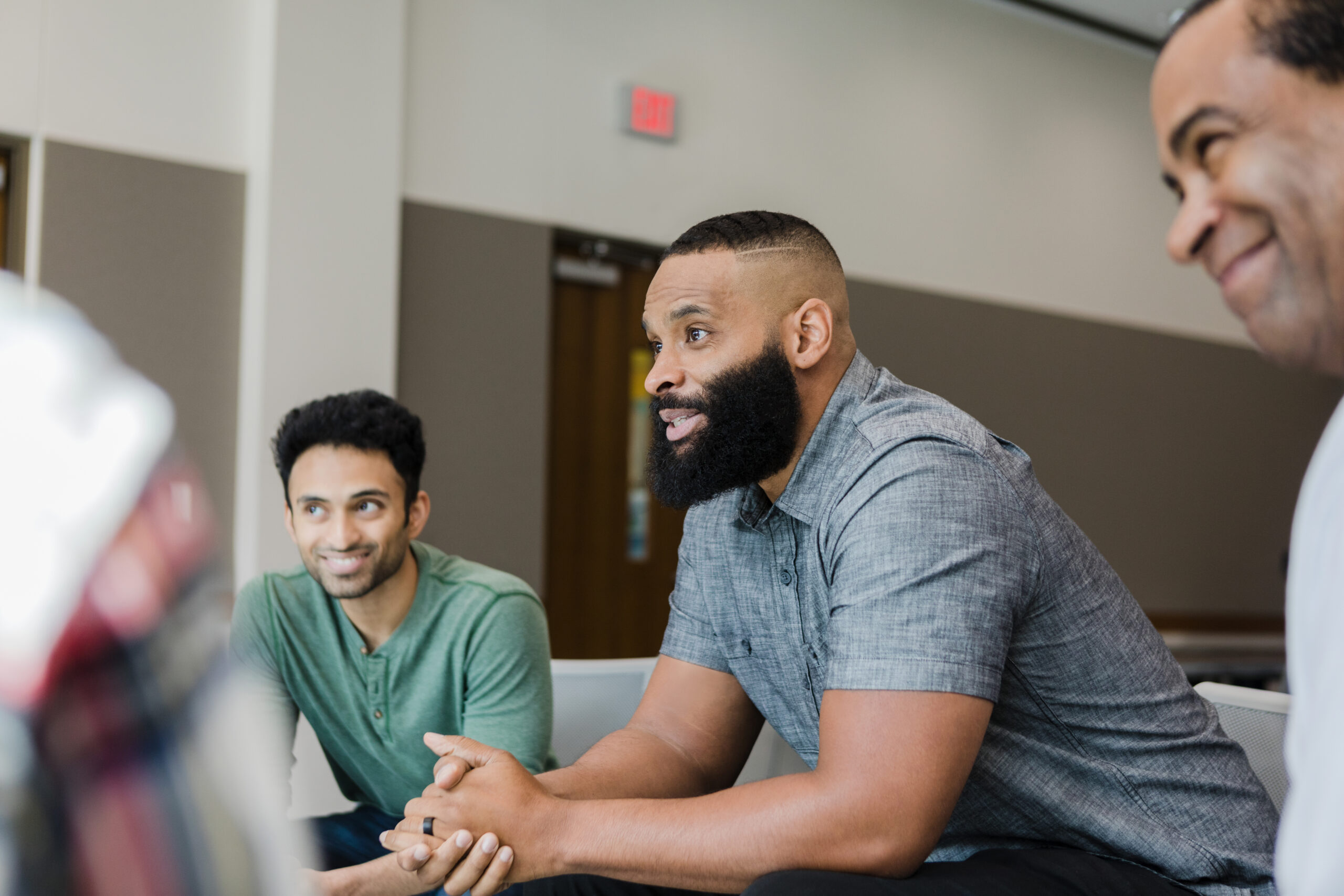 Diverse group of people smiling and engaged in a supportive meeting environment.